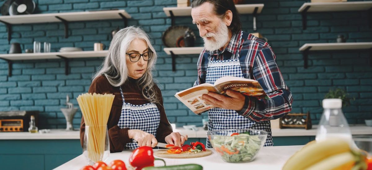 Elderly couple preparing a meal together in a stylish kitchen, emphasizing bonding and teamwork.