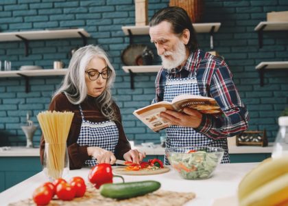 Elderly couple preparing a meal together in a stylish kitchen, emphasizing bonding and teamwork.
